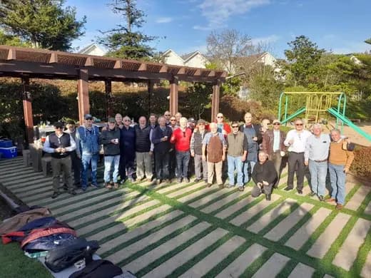 Socios reunidos bajo una pérgola en una actividad al aire libre.