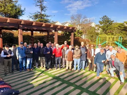 Grupo de socios posando al aire libre durante un asado de la corporación.